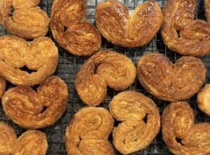 Baked golden flaky palmiers on top of a cooling rack